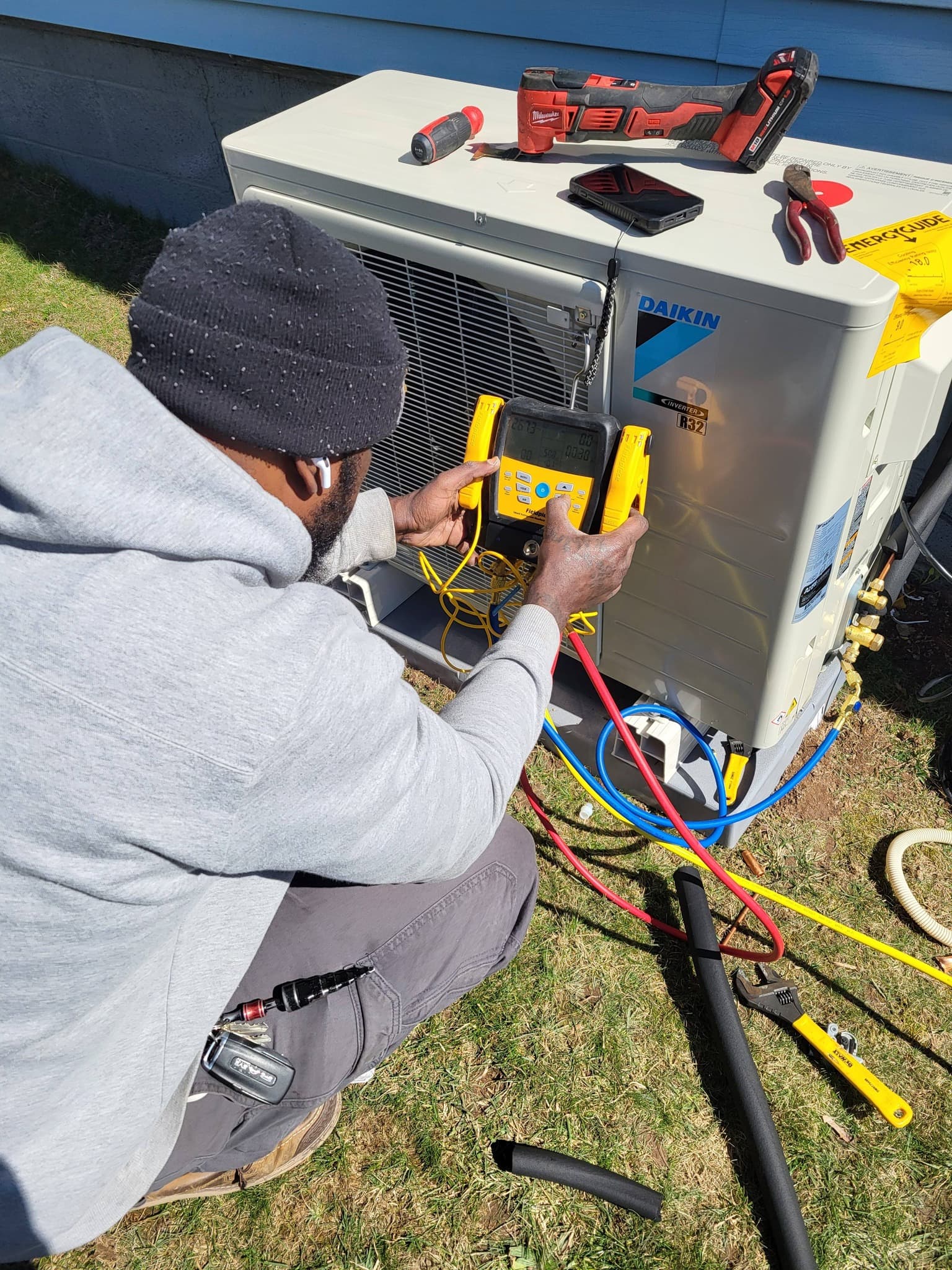 Air Benders technician using gauges on a Daikin condenser at a customer's home